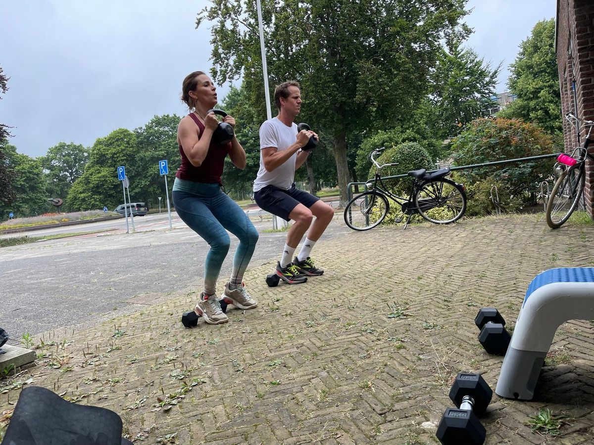 Twee mensen doen een uitvalspas met dumbells op straat
