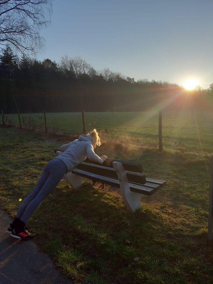 Iemand traint bij zonsopgang op een bankje in het veld